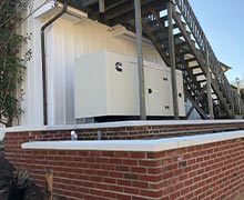 A large commercial generator installed neatly on the side of a building under a staircase