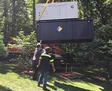 A Cummins D1703 industrial generator with a Kubota 4 cycle liquid cooled engine being lowered by crane to where it will be set