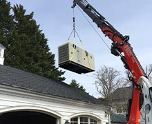 A Cummins V2203 industrial generator with a heavy duty Kubota engine being lowered by crane over an Annapolis homeowners garage