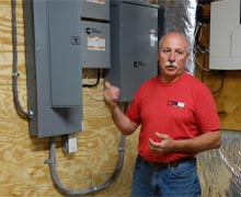 Ken Kloster showing the transfer switch and load shedding boxes to a customer