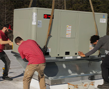 A large air conditioning unit being set onto a roof curb adapter