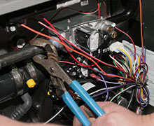 The hands of a heating and air technician who is using channel locks during a new AC unit installation
